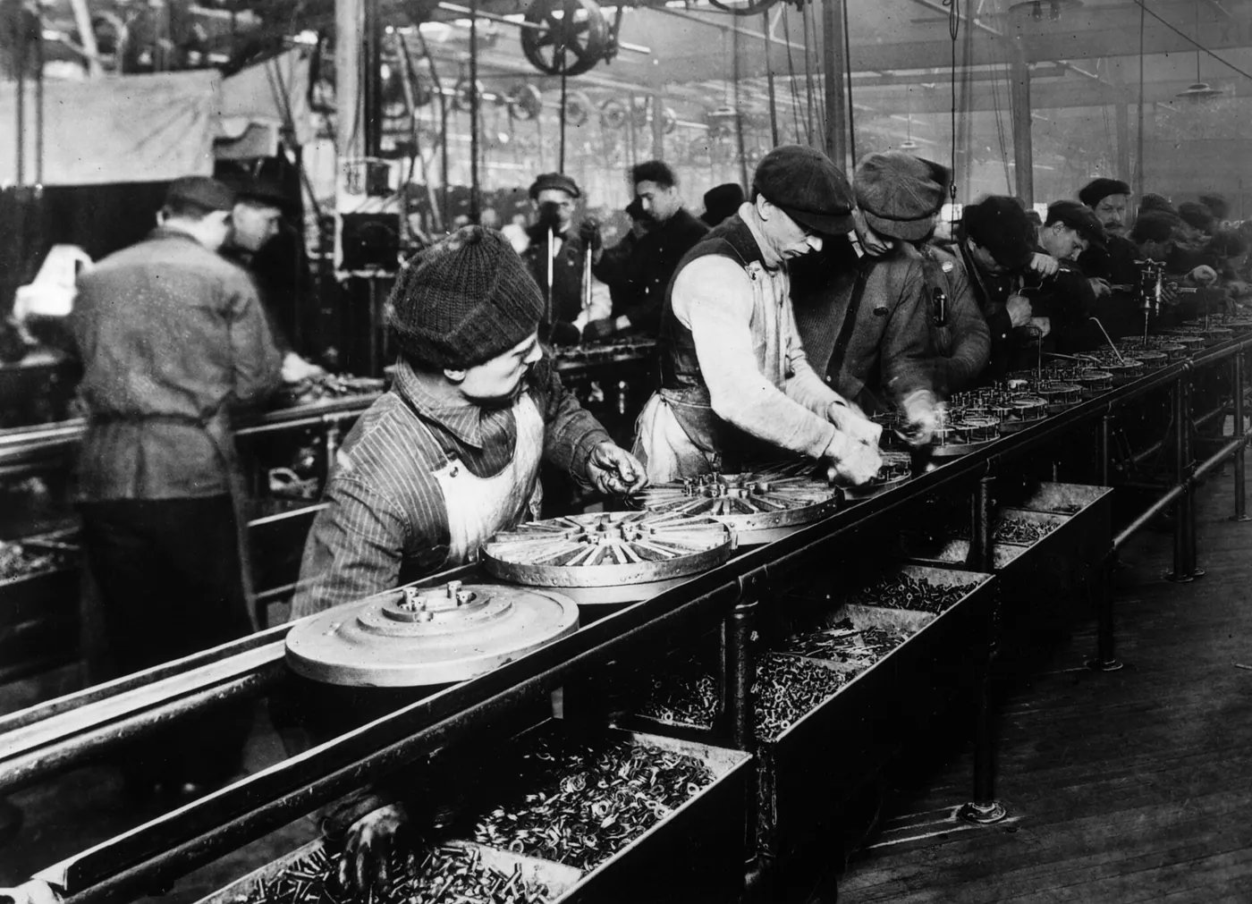 The flywheel-magneto line at Ford’s Highland Park plant, 1913, the company’s first moving assembly line. The parts moved past workers who stayed in place.