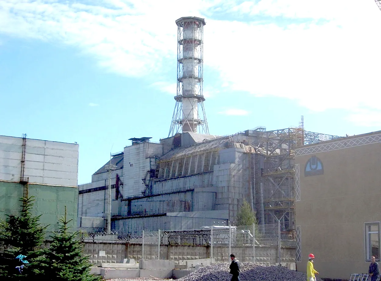 Unit four at Chernobyl in 2006, with the shelter built over it after the accident and the security perimeter in front. Inside the fence it remains a closed zone.
